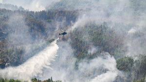 28.07.2022, Sachsen, Schmilka: Ein Hubschrauber der Bundespolizei fliegt mit einem Löschwasser-Außenlastbehälter um einen Waldbrand im Nationalpark Sächsische Schweiz zu löschen. Foto: Robert Michael/dpa +++ dpa-Bildfunk +++