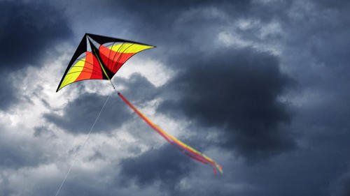 Colorful kite is flying and rain clouds in dramatic sky, Greece.
