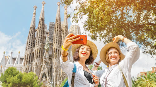 Zwei Frauen machen ein Selfie vor eine Kathedrale.