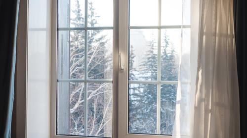 Fenster mit Ausblick auf weiße Winterlandschaft