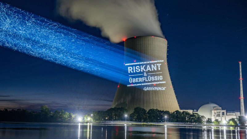 12.09.2022, Bayern, Essenbach: Greenpeace-Aktivisten projizieren "Riskant & überflüssig" an den Kühlturm am Kernkraftwerk Isar 2. Foto: Armin Weigel/dpa +++ dpa-Bildfunk +++
