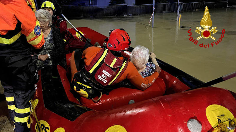 HANDOUT - 16.09.2022, Italien, Senigallia: Feuerwehrleute helfen älteren Frauen aus einem Schlauchboot, die sie aus ihren Häusern gerettet haben. Heftige Regenfälle und Überschwemmungen an der italienischen Adriaküste haben Menschenleben gefordert, w