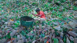 ARCHIV - 04.04.2022, Bangladesch, Noakhali: Ein Mitarbeiter sitzt in einer Recyclingfabrik auf einem Haufen Plastikflaschen und sortiert diese in einen Korb. (zu dpa «Internationale Koalition arbeitet an Abkommen für weniger Plastikmüll») Foto: Joy Saha/ZUMA Press Wire/dpa +++ dpa-Bildfunk +++