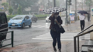 19.09.2022, Japan, Tokio: Eine Fußgängerin geht während starker Regenfälle mit einem Regenschirm den Gehweg entlang. Bei dem ungewöhnlich heftigen Taifun «Nanmadol» sind in Japan mehrere Menschen ums Leben gekommen und verletzt worden. In Hunderttausenden Haushalten fiel zeitweise der Strom aus, der Bahn- und Flugverkehr war beeinträchtigt. Foto: Zhang Xiaoyu/XinHua/dpa +++ dpa-Bildfunk +++