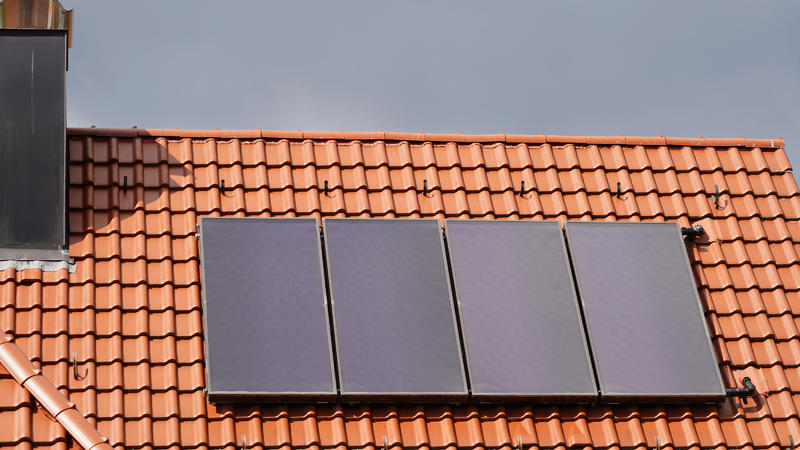 Solarthermie Module auf einem Wohnhaus Dach unter Gewitterwolken.