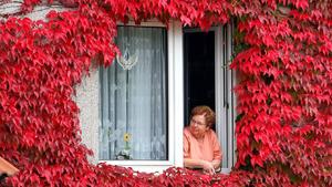 Eine Frau schaut am Donnerstag (20.09.2007) in Irxleben (Bördekreis) aus dem Fenster eines Hauses, das mit wildem Wein bewachsen ist. Die Herbstsonne und die schon kühlen Nächte haben das Laub rot gefärbt. In den kommenden Tagen soll das Wetter in Sachsen-Anhalt mild undsonnig werden. Foto: Peter Förster/lah +++(c) dpa - Bildfunk+++