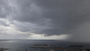23.10.2019, Spanien, Palma de Mallorca: Dunkle Regenwolken hängen über der Bucht und dem Hafen, in dem zwei Kreuzfahrtschiffe liegen. Rund ums Mittelmeer haben heftige Unwetter vielerorts Überflutungen und Schäden  verursacht. Foto: Clara Margais/dpa +++ dpa-Bildfunk +++