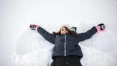 Girl smiling while making snow angel in the snow in front yard United States, Iowa, Grimes PUBLICATIONxINxGERxSUIxAUTxONLY CRLIPF191001-197530-01