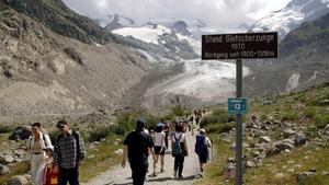 Zahlreiche Wanderer pilgern am 22.7.2003 zum Morteratschgletscher bei Pontresina im Oberengadin an einem Schild vorbei, dass den Stand der Gletscherzunge aus dem Jahr 1970 markiert. Auf der Suche nach Abkühlung spazieren sie von der Station Morteratsch zum Fuße des Morteratschgletschers im Berninagebiet. Dabei wird der Fußmarsch Jahr für Jahr um einige Minuten länger. Wie bei praktisch allen Schweizer Gletschern schwinden auch die Eismassen des Morteratschgletschers in horrendem Tempo, in diesem Sommer noch schneller als sonst.