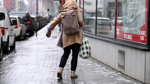 19.12.2022, Hessen, Kassel: Eine Frau schlittert über den vereisten Gehweg. Nach tagelangem Frost hat eine Warmfront mit Regen für Blitzeis in vielen Regionen Hessens gesorgt. Foto: Uwe Zucchi/dpa +++ dpa-Bildfunk +++