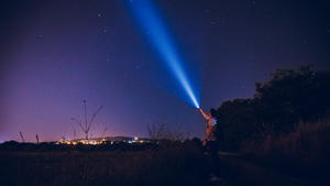 Mensch strahlt Licht in den Himmel auf der Suche nach Außerirdischen