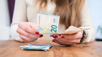 Eine junge Frau sitzt am 16.02.2017 in einem Wohnzimmer in Hamburg und zaehlt Geld