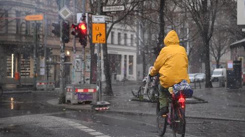 Ein Fahrradfahrer fährt durch den Schneeregen in Kreuzberg.
