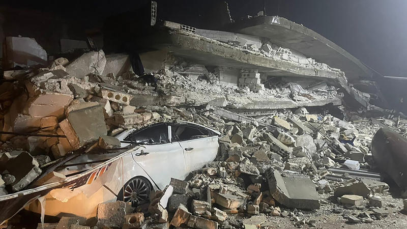 06.02.2023, Syrien, Azmarin: Ein Auto ist unter den Trümmern eines eingestürzten Gebäudes in der Stadt Azmarin in der nordsyrischen Provinz Idlib zu sehen. Zwei heftige Erdbeben haben kurz nacheinander am frühen Montagmorgen den Südosten der Türkei e