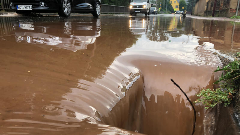 ARCHIV - 26.08.2022, Sachsen, Oberlungwitz: Der Dorfbach ist nach Starkregen über die Ufer getreten und hat eine Straße geflutet. Der Deutsche Wetterdienst DWD stellt am 21. März die Klima-Bilanz für das Jahr 2022 vor. Foto: David Rötzschke/dpa +++ d