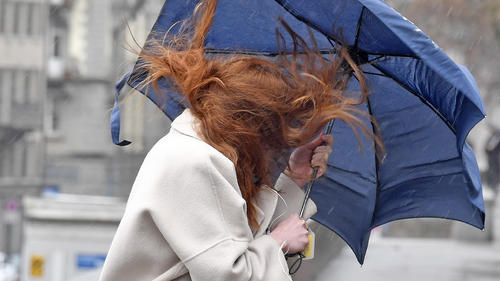 Eine junge Frau mit Regenschirm kaempft sich mit zerzausten Haaren durch den Regen und den Wind in Zuerich am Freitag, 15. Maerz 2019. (KEYSTONE/Walter Bieri)