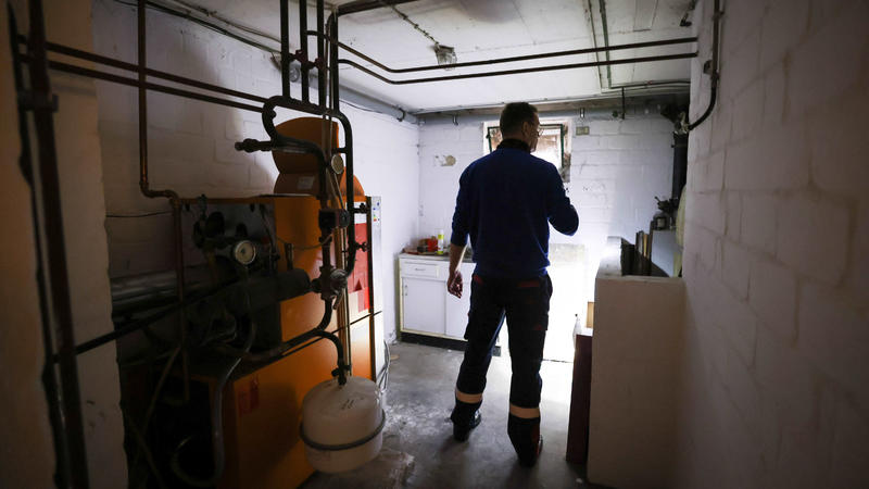 Ein Mitarbeiter eines Diesel- und Heizöl-Unternehmens prüft die Kunststofftanks in einem Heizungskeller bei der Heizöllieferung für ein Einfamilienhaus. 