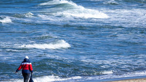 11.03.2023, Mecklenburg-Vorpommern, Kühlungsborn: Eine Spaziergängerin ist bei Sonnenschein und frostigen Temperaturen bei stürmischer See am Strand unterwegs. Einwohner und Tagesgäste nutzen das schöne Wetter zu Ausflügen an die Ostseeküste. Foto: Jens Büttner/dpa +++ dpa-Bildfunk +++