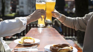 ARCHIV - 28.03.2021, Baden-Württemberg, Tübingen: Zwei Menschen sitzen bei gutem Wetter in einem Biergarten und stoßen mit einem Bier an.Der Regenschirm kann dieses Wochenende im Schrank bleiben, doch die Sonnencreme ist bei Ausflügen oder beim Baden ein Muss. (zu dpa: «Sonne satt - Meteorologen erwarten schöne Pfingsten im Südwesten»). Foto: Tom Weller/dpa +++ dpa-Bildfunk +++