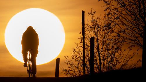 ARCHIV - 09.11.2021, Hessen, Frankfurt/Main: Ein Fahrradfahrer fährt im Sonnenuntergang. Mit Blick auf die Klimakrise ist Hoffnung nicht das erste Wort, das einem in den Sinn kommt. Hoffnungsvolle Klimasignale gibt es aber - die Deutsche Presse-Agentur hat zehn davon zusammengestellt. (zu dpa "Nicht mehr zu retten? Zehn Klima-Signale, die Hoffnung geben") Foto: Sebastian Gollnow/dpa +++ dpa-Bildfunk +++