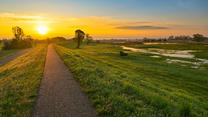 24.04.2023, Brandenburg, Lebus: Der Sonnenaufgang scheint über dem Oder-Neiße-Radweg am Deich nahe dem deutsch-polnischen Grenzfluss Oder. Foto: Patrick Pleul/dpa +++ dpa-Bildfunk +++