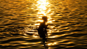15.07.2023, Bayern, München: Ein Junge planscht am Abend bei Sonnenuntergang im flachen Wasser des Wörthsee im Fünf Seenland, westlich der bayerischen Landeshauptstadt. Foto: Peter Kneffel/dpa +++ dpa-Bildfunk +++
