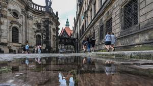 20.07.2023, Sachsen, Dresden: Eine Pfütze hat sich nach einem Regenguss zwischen der Hofkirche und dem Residenzschloss auf den Pflastersteinen auf dem Theaterplatz gebildet. Foto: Robert Michael/dpa +++ dpa-Bildfunk +++