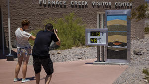 11.07.2023, USA, Death Valley National Park: Menschen bleiben stehen, um Fotos von einem Thermostat zu machen, der 119° Fahrenheit (48° Celsius) im Furnace Creek Besucherzentrumim Death Valley National Park, Kalifornien, anzeigt. Der Juli ist der heißeste Monat im Park mit einer durchschnittlichen Höchsttemperatur von 116 Grad (46,5 Celsius). Foto: Ty ONeil/AP/dpa +++ dpa-Bildfunk +++