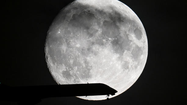 29.08.2023, Hessen, Frankfurt/Main: Ein Passagierflugzeug ist im Landeanflug auf den Frankfurter Flughafen, während der Mond am Abendhimmel leuchtet. Nach einem großen Vollmond zum Start in den August zeigt sich der Erdtrabant in der Nacht auf den 31. August erneut in seiner vollen Pracht. Wie schon zu Monatsanfang ist der Vollmond der Erde besonders nah, er sieht dadurch etwas größer aus als sonst. Foto: Arne Dedert/dpa +++ dpa-Bildfunk +++