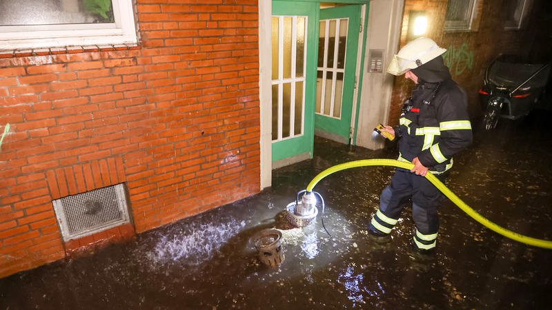 ARCHIV - 23.06.2023, Hamburg: Einsatzkräfte der Feuerwehr pumpen Regenwasser aus einem Keller auf die Straße. (Zu dpa: «91 Millionen Euro Schäden durch Starkregen in Hamburg in 20 Jahren») Foto: Bodo Marks/dpa +++ dpa-Bildfunk +++