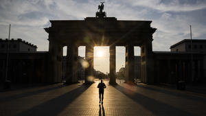 dpatopbilder - 19.08.2023, Berlin: Ein Mann läuft bei aufgehender Sonne durch das Brandenburger Tor. Die Menschen in Berlin und Brandenburg müssen sich am Samstag auf starke bis extreme Wärme einstellen. Foto: Christoph Soeder/dpa +++ dpa-Bildfunk +++