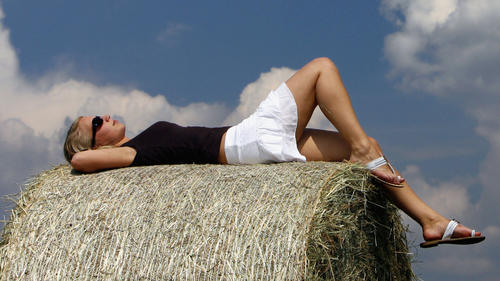 Auf einem Heuballen liegend genießt eine junge Frau am Samstag (09.06.2007) auf einem Feld nahe Zeilitzheim (Unterfranken) die Sonne. Laut Vorhersage der Meteorologen zeigt sich das Wetter in Bayern am Sonntag (10.06) mit viel Sonne und Höchstwerten zwischen 28 und 31 Grad. Foto: Daniel Karmann dpa/lby +++(c) dpa - Bildfunk+++