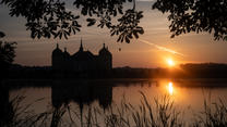 26.09.2023, Sachsen, Moritzburg: Die Sonne geht am Morgen hinter dem Schloss Moritzburg, dem einstigen Jagdschloss der Wettiner bei Dresden, auf. Foto: Robert Michael/dpa +++ dpa-Bildfunk +++
