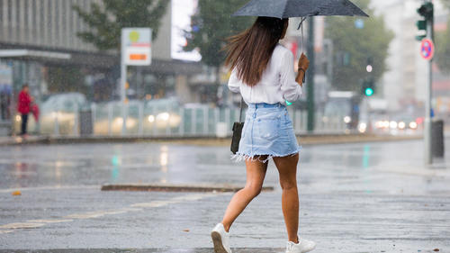 13.08.2018, Nordrhein-Westfalen, Düsseldorf: Eine Frau geht bei einem starken Regenschauer über eine Straße. Foto: Rolf Vennenbernd/dpa