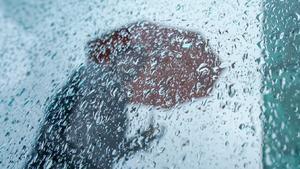 07.10.2023, Hamburg: Eine Passantin geht mit ihrem Regenschirm an einer Scheibe mit Regentropfen in der Innenstadt vorbei. Für heute sind weitere Regenschauer vorhergesagt. Foto: Marcus Brandt/dpa +++ dpa-Bildfunk +++