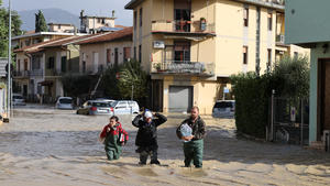 03.11.2023, Italien, Toskana: Menschen gehen im Hochwasser über eine überschwemmte Straße. Schwere Unwetter mit heftigen Regenfällen haben die mittelitalienische Region Toskana in der Nacht zum Freitag heimgesucht. Foto: Str/Xinhua/dpa +++ dpa-Bildfunk +++