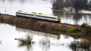 18.11.2023, Baden-Württemberg, Unlingen: Ein Regionalzug der Deutschen Bahn fährt auf einem Bahndamm durch die vom Hochwasser der Donau überfluteten Wiesen Foto: Thomas Warnack/dpa +++ dpa-Bildfunk +++