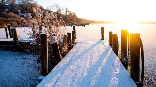 Die Sonne geht bei winterlichem Wetter im Ortsteil Dreibergen über dem zugefrorenen Zwischenahner Meer auf.