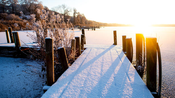 Die Sonne geht bei winterlichem Wetter im Ortsteil Dreibergen über dem zugefrorenen Zwischenahner Meer auf.