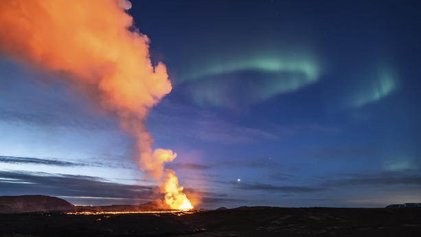 dpatopbilder - 25.03.2024, Island, Grindavik: Die aus dem Vulkan fließende Lava ist vor dem Hintergrund der Nordlichter zu sehen. Foto: Marco di Marco/AP/dpa +++ dpa-Bildfunk +++