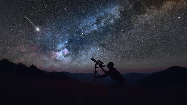 Sternengucker beobachtet den Nachthimmel mit Sternschnuppe im Hintergrund