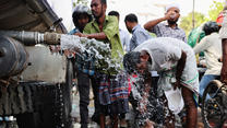A man washes his head as people drink water from a tanker during the countrywide heatwave, in Gulistan area, in Dhaka, Bangladesh, April 22, 2024. REUTERS/Mohammad Ponir Hossain