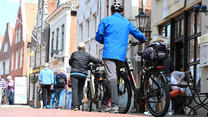 04.05.2024, Niedersachsen, Leer: Zwei Fahrrad-Touristen ziehen mit ihren Rädern durch die Altstadt. Sommerliches Wetter herrscht am ersten Mai-Wochenende in Ostfriesland. Foto: Lars Penning/dpa +++ dpa-Bildfunk +++