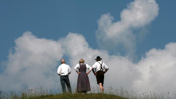 Vor großen Wolken stehen am Samstag (09.06.2007) Spaziergänger auf einem Hügel bei Schliersee im Kreis Miesbach (Oberbayern). Wegen der schwülwarmen Luftmassen wird die Gewittergefahr auch in den nächsten Tagen weiter zunehmen. Foto: Frank Leonhardt dpa/lby +++(c) dpa - Bildfunk+++