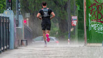 02.05.2024, Hessen, Frankfurt/Main: Ein Mann joggt bei strömendem Regen über die Flößerbrücke. Blitze, Donner und Starkregen sind über die Rhein-Main-Region hinweggezogen. Foto: Andreas Arnold/dpa +++ dpa-Bildfunk +++