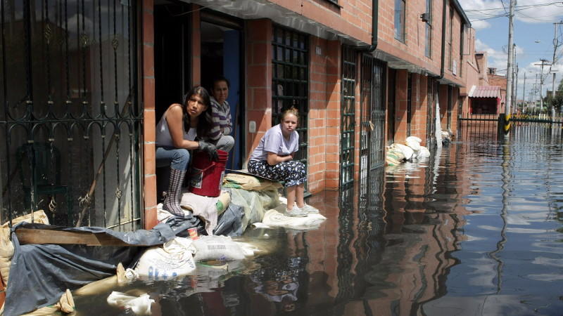 ACHTUNG: SPERRFRIST  23. März 1200 - ARCHIV - Frauen warten vor ihren teilweise unter Wasser stehenden Häusern am 09.12.2011 in Bogota (Kolumbien) auf Hilfe. In Kolumbien hatte das Wetterphämonen La Nina für Überschwemmungen gesorgt. Die Erderwärmung