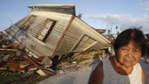 A survivor stands next to her house, which collapsed during Super Typhoon Haiyan, in Bantayan island off northern Cebu in central Philippines November 16, 2013. Survivors began rebuilding homes destroyed by Haiyan, one of the world's most powerful typhoons, and emergency supplies flowed into ravaged Philippine islands, as the United Nations more than doubled its estimate of people made homeless to nearly two million.      REUTERS/Erik De Castro (PHILIPPINES  - Tags: ENVIRONMENT DISASTER)  