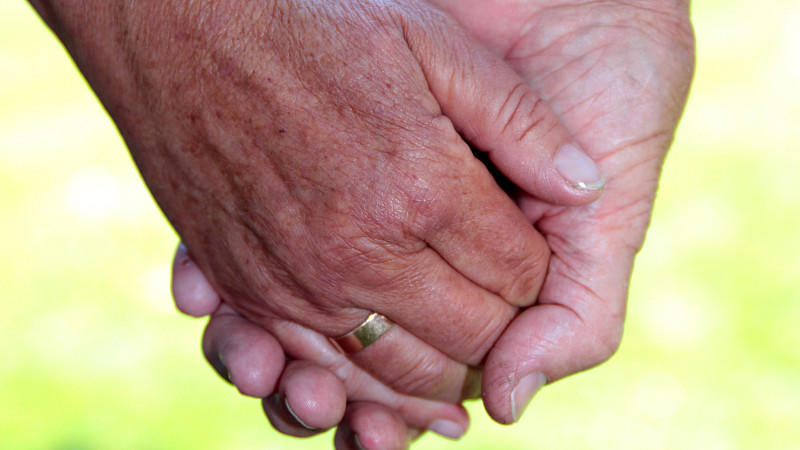 Ein älteres Ehepaar hält Händchen