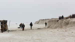 Inselbesucher gehen am 08.12.2013 auf der ostfriesischen Insel Norderney (Niedersachsen) am Strand entlang, wo nach dem Orkan Xaver große Teile der Dünen weggeschwemmt wurden. Eine genaue Bilanz sei erst nach einer Laservermessung aus der Luft in den kommenden Tagen möglich. Foto: dpa +++(c) dpa - Bildfunk+++