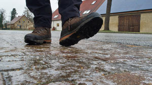 Vorsichtig geht ein Mann am 20.01.2014 über einen vom Eis spiegelglatten Bürgersteig in Sieversdorf (Brandenburg). Das Eis auf dem Gehweg ist vom gestreuten Streusalz teilweise schon geschmolzen. Leichter Nieselregen ist am Morgen in weiten Teilen von Brandenburg auf dem kalten Boden sofort gefroren. Vielerorts sind Straßen und Gehwege extrem glatt. Foto: Patrick Pleul/dpa +++(c) ZB-FUNKREGIO OST - Honorarfrei nur für Bezieher des ZB-Regiodienstes+++
